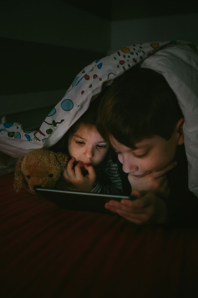 Siblings looking at the tablet in the dark