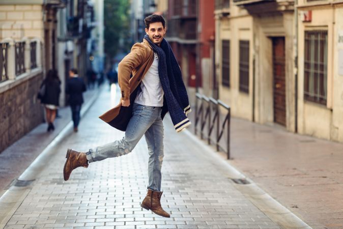 Man in scarf leaping in the street