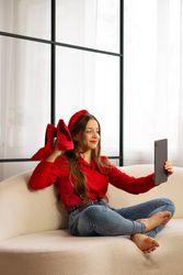Teen girl on sofa taking selfie holding red heels.