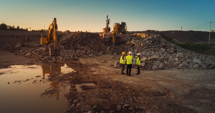 Aerial Drone Shot Of Construction Site With Heavy Machinery On Sunny Day: Diverse Team of Real Estate Developers Discussing Project. Civil Engineer, Architect, Urban Planner Talking And Using Tablet.