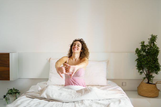 Smiling woman stretching in bed as she wakes up