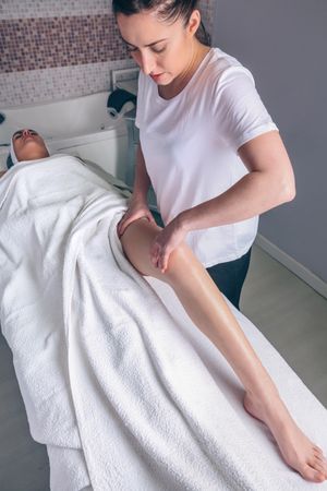 Woman receiving massage on leg in beauty center