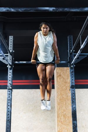 Hispanic sportswoman exercising on crossbar