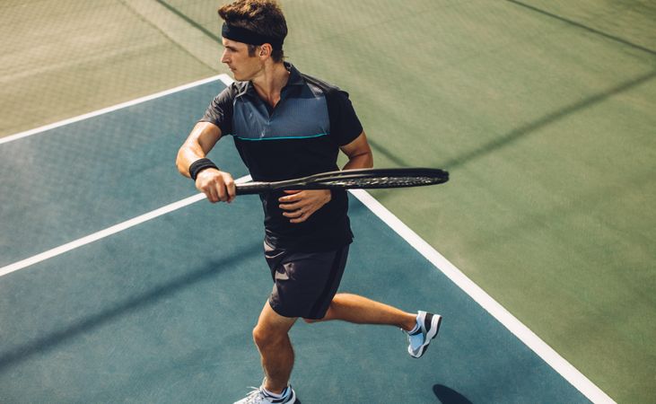 Pro tennis player practicing forehands on a club hard court