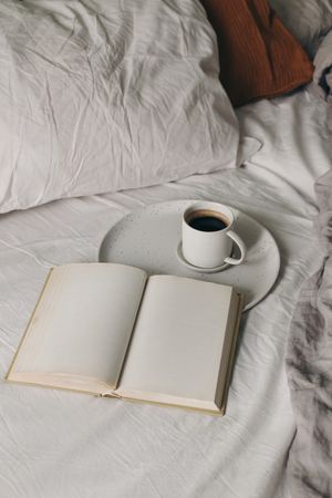 Cup of coffee, espresso with open book, diary mockup on bed sheet