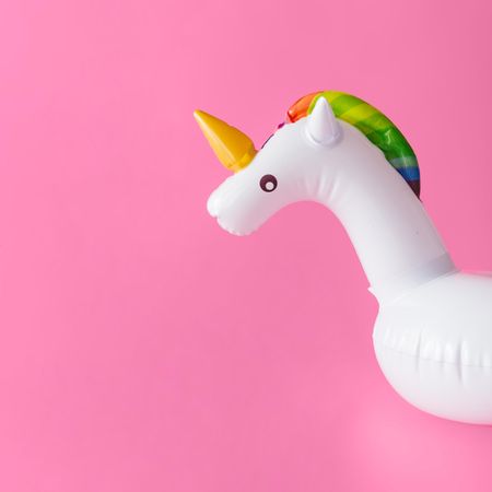 Inflatable unicorn pool toy on pastel pink background