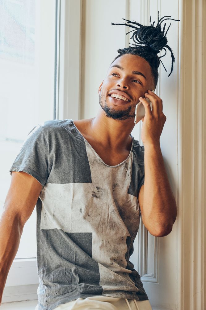 Black braided male using smartphone