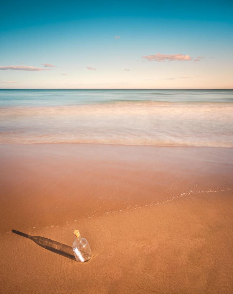 Bottle in sand near sea