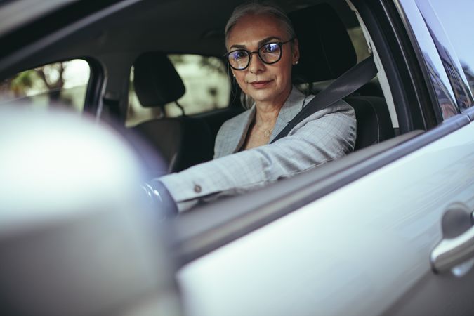 Mature woman driver a car looking at camera