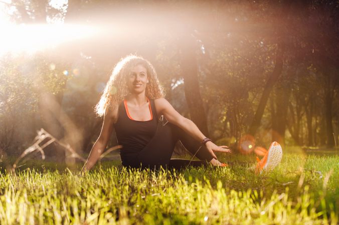 Happy woman stretching on sunny meadow