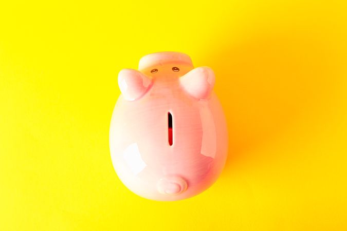 Happy piggy bank on yellow background, space for text and top view. Finance, saving money