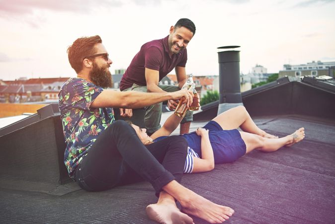 Woman lying down on rooftop relaxing with friends and beers
