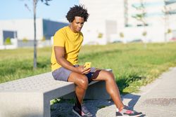 Man sitting outside on phone after exercising