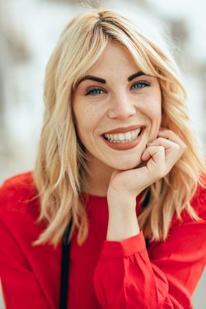 Blonde woman smiling with head resting on her hand