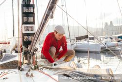 Sailor on yacht arranging the covering at sunset 47PJBb