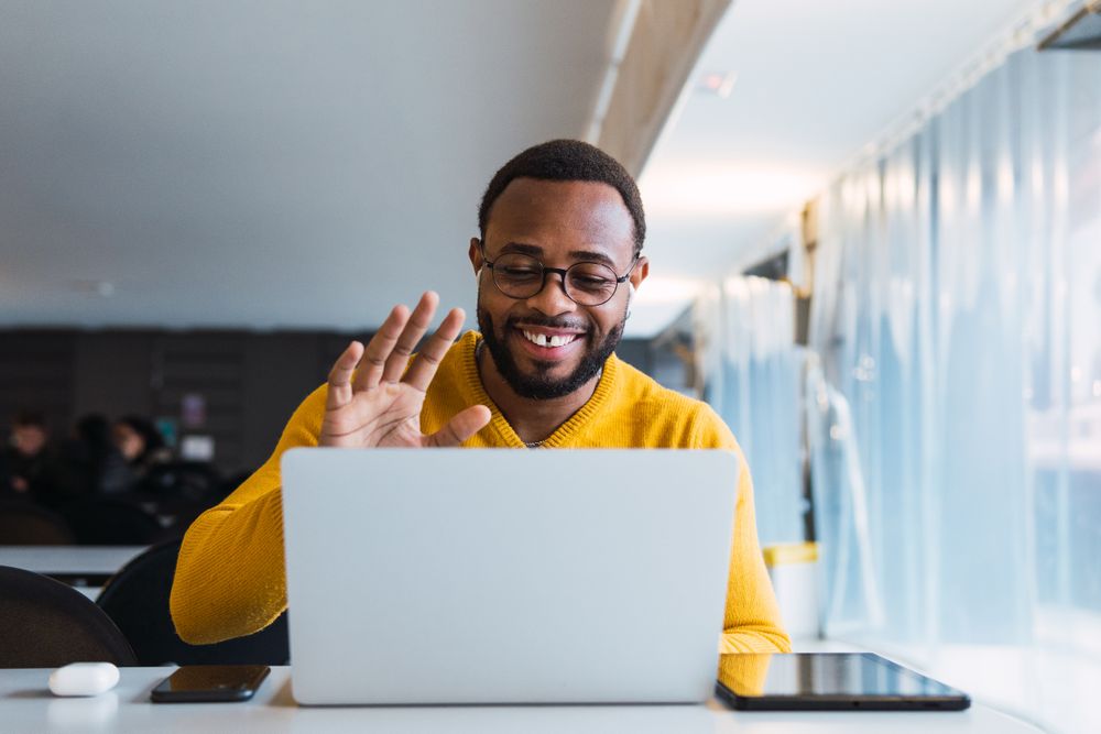 Smiling Black man calling on laptop in workspace