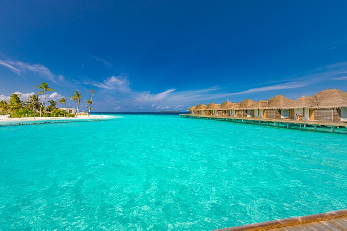 Overwater bungalows facing a small island with palm trees