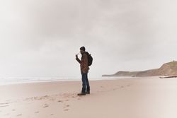 Man smoking pipe on sand shore near water