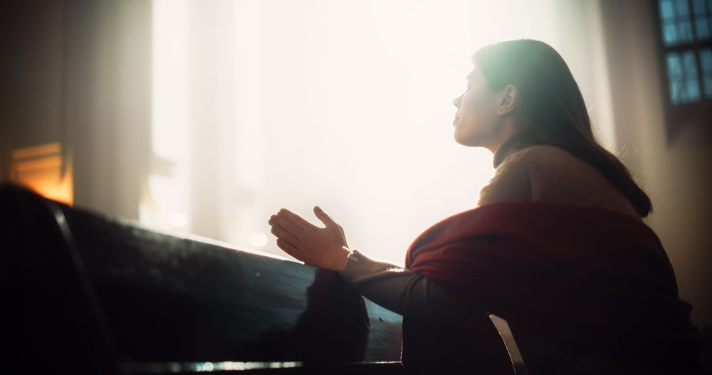 Young Christian Woman Sits Piously in Majestic Church, with Folded Hands