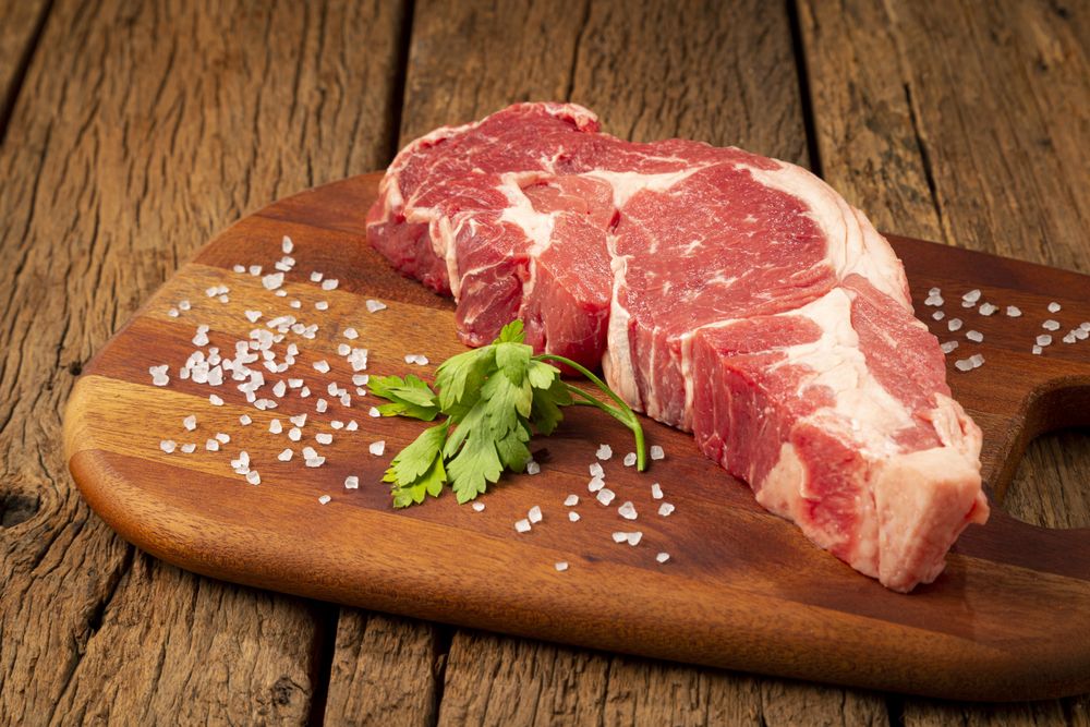 Raw ancho meat ready to roast on a wooden cutting board.