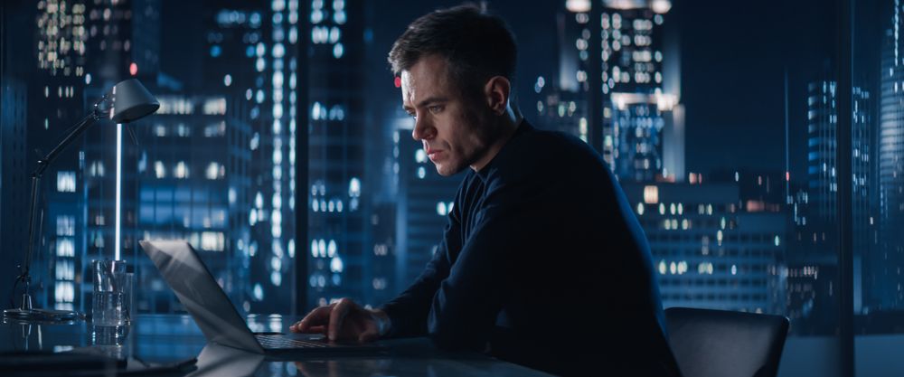 Successful Businessman Working on Laptop Computer in Big City Office Late At Night.