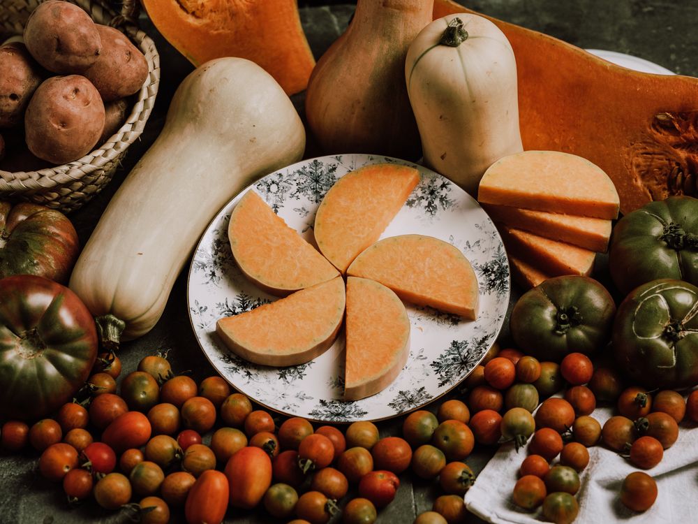 Composition of tomatoes sliced nutmeg pumpkin on plate and potatoes
