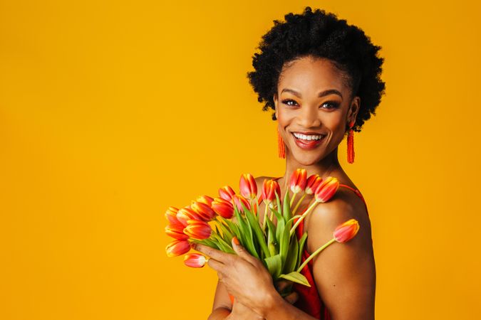 Happy Black woman holding bouquet of tulips