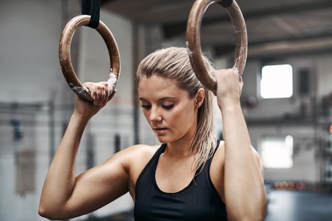 Healthy and serious woman getting focused before workout on gymnastic rings