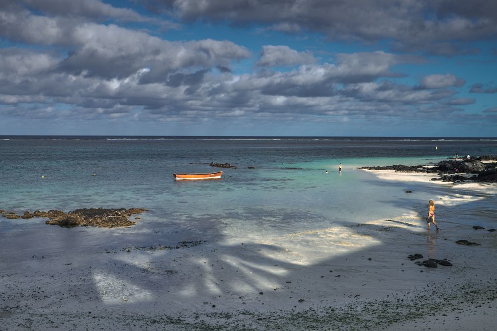 Boat in a lagoon with some people on a tropical beach