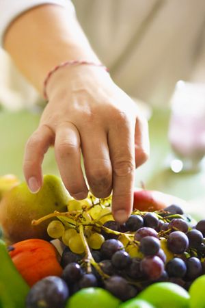 A man reaching for some grapes.