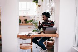 Man sitting in coffee shop with drink and laptop