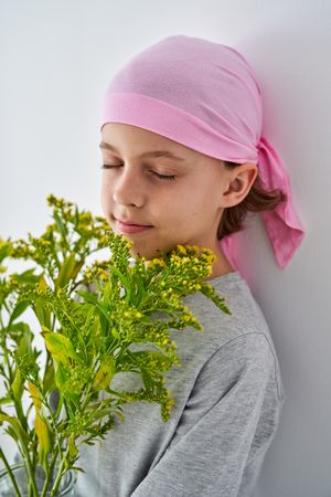 Kid in pink headband enjoying smell of wildflowers