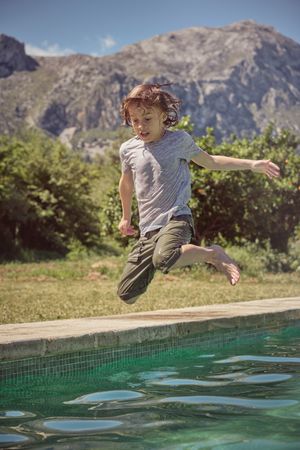 Cute kid jumping into water of swimming pool