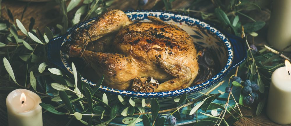 Centerpiece of roast chicken surrounded with decorative branches, and two candles