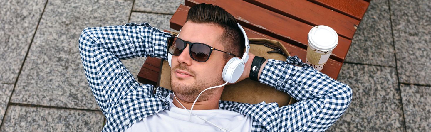 Man with headphones lying on a bench