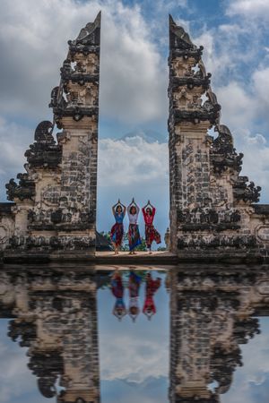 Three women in traditional outfits standing between pillars at temple of Lempuyang Luhur in Bali, Indonesia