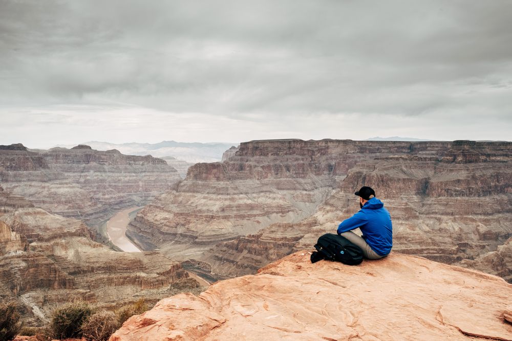 Male relaxing on cliff and admiring picturesque view