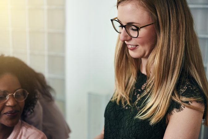 Woman in glasses looking down and smiling amongst her colleagues