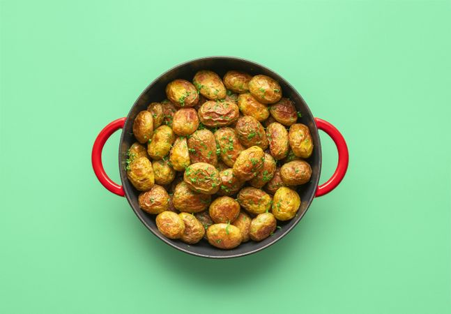 Roasted baby potatoes in a pan, top view on a green background