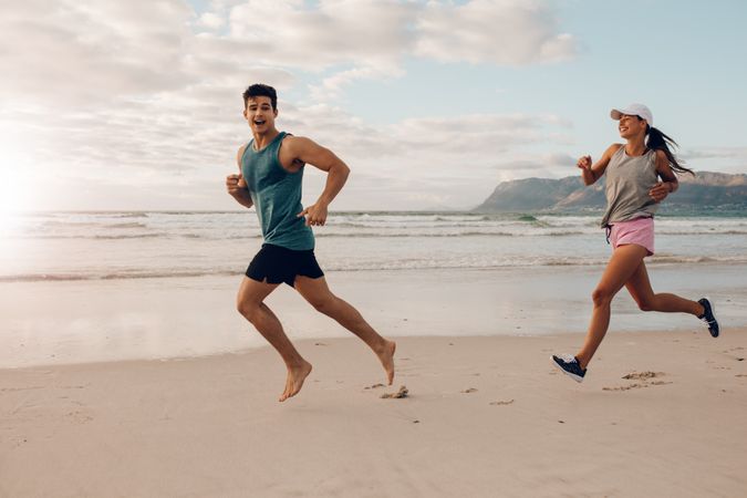 Happy young couple of runners on the beach