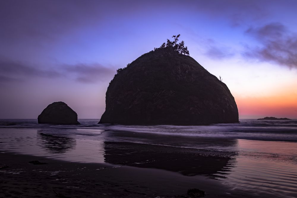 Two large rocks under gradient purple orange sky