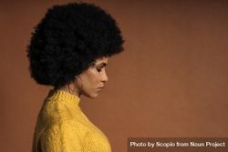Side view of sad woman yellow knit sweater against brown background 0KZy7b