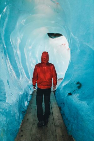 Back view of person in red jacket walking in an iced cave