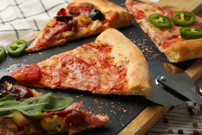 Board with tasty pizza slices on wooden background