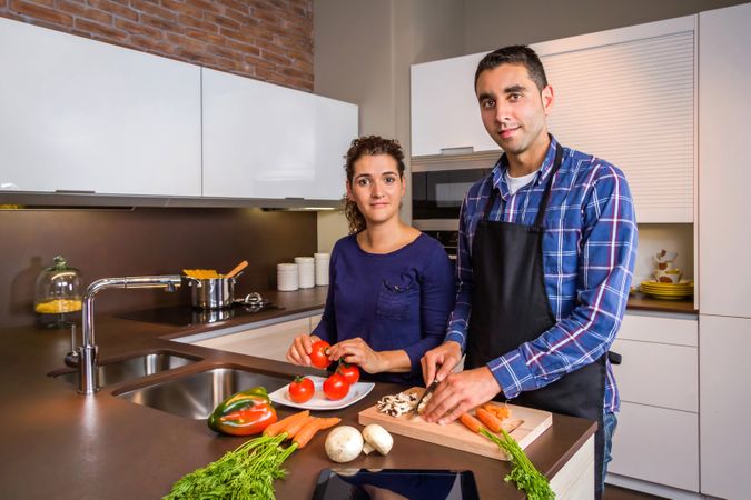 Portrait of couple cutting vegetables for dinner with space for text