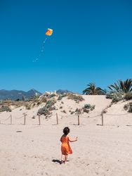 Toddler girl playing with kite on sandy beach