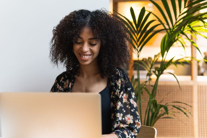 Smiling woman surfing internet on laptop indoors