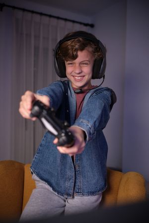 Cheerful boy playing videogame with gamepad