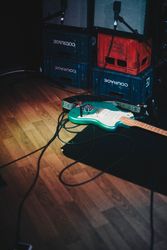 Teal electric guitar and amplifiers stacked on crates on stage at concert venue