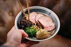 Crop person with chopsticks having bowl of ramen in cafe